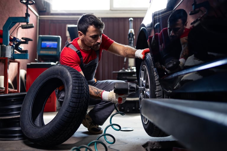 Wheel repairman using tool to remove damaged tire from the car