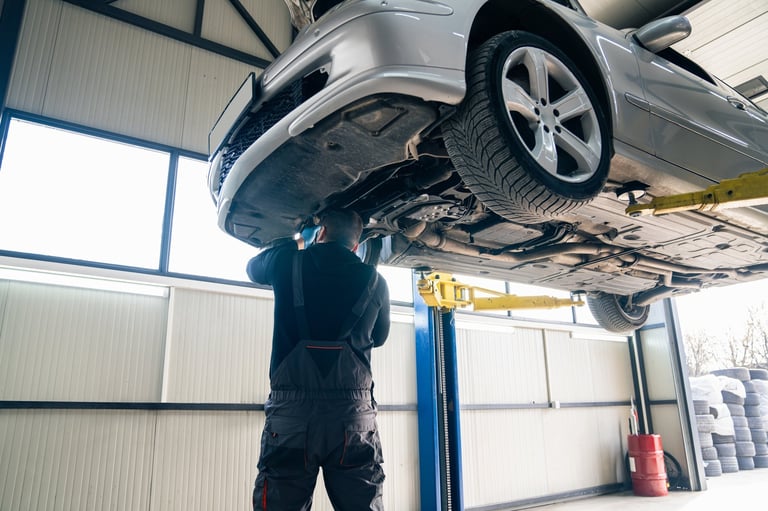Serviceman checks car suspension on a column lift in car service