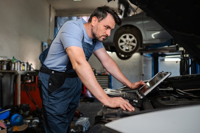 Mechanic using diagnostic software on a laptop to check a car engine